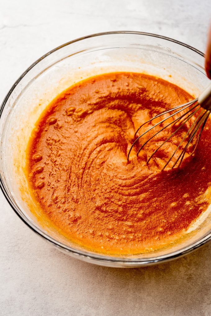 The wet ingredients for pumpkin cake in a bowl with a whisk.