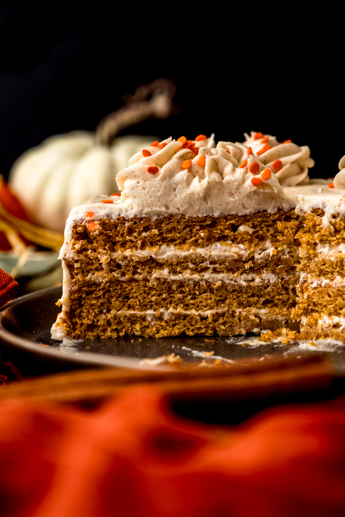 A pumpkin layer cake on a platter sliced so you can see the cross section of it.