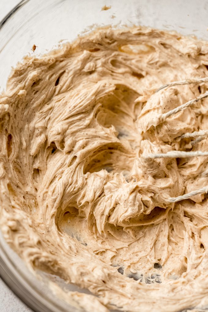 Closeup of maple cinnamon cream cheese frosting in a bowl with electric beaters.